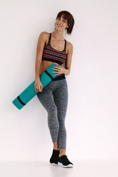 Smiling woman with yoga mat in studio